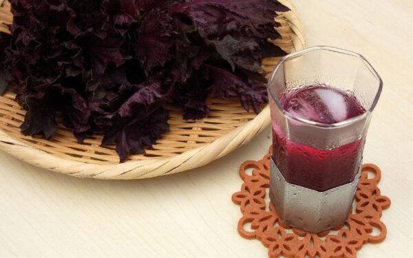 ザルに乗せた赤シソの葉とグラスに入った紫蘇ジュース